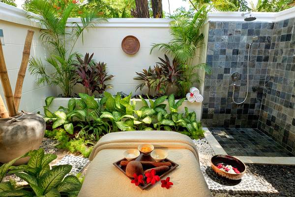 Außenbereich des Kurumba Maldives Hotels mit einer Spa-Behandlung und Pflanzen.