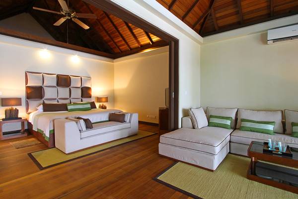 Innenansicht der Suite im Kurumba Maldives Hotel mit Bett, Sofa und Couchtisch.