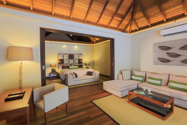 Innenansicht der Suite im Kurumba Maldives Hotel mit Bett, Wohnzimmer und Essbereich.