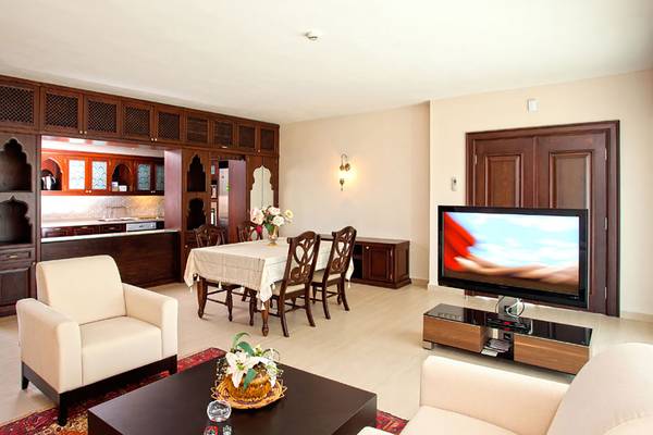 Wohnzimmer im Salmakis Resort & Spa mit Fernseher, Tisch und Stühlen.