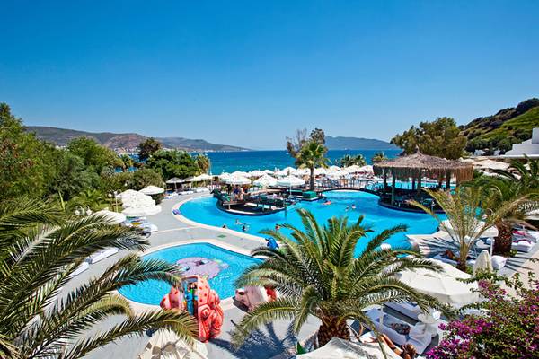 Luftaufnahme des Salmakis Resort & Spa Pools mit Meerblick und vielen Liegen und Sonnenschirmen
