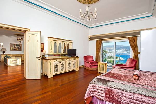 Innenansicht der Suite im Salmakis Resort & Spa mit großem Bett, Sitzbereich und Meerblick.