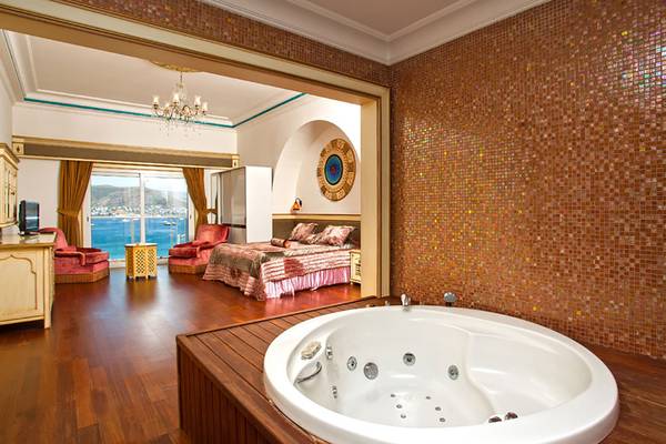 Suite im Salmakis Resort & Spa mit Jacuzzi, Bett und Blick auf das Meer.