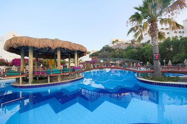 Pool im Salmakis Resort & Spa mit einer Hütte und einer Brücke.