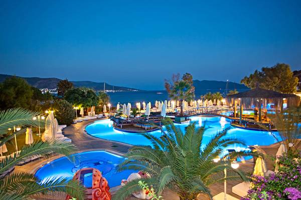 Salmakis Resort & Spa Pool bei Nacht mit Blick auf den Ozean und Hügeln.