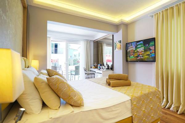 Ein geräumiges Hotelzimmer mit einem Bett, Kissen, Decken, einem Fernseher und einer offenen Terrassentür im Selectum Family Comfort Side Hotel.