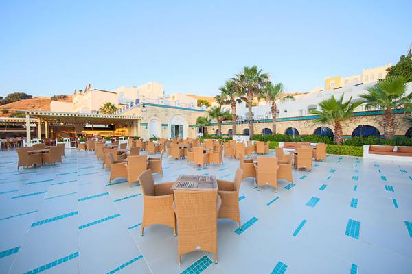 Außenbereich des Salmakis Resort & Spa mit vielen Tischen und Stühlen auf der Terrasse.