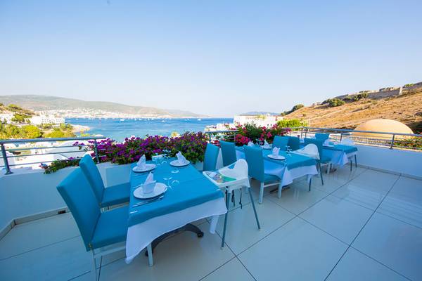 Terrasse mit blauen Esstischen im Salmakis Resort & Spa mit Blick auf das Meer.