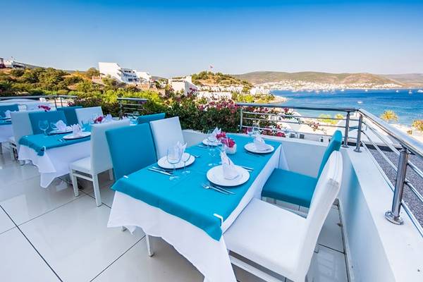 Terrasse mit blauen Tischen im Salmakis Resort & Spa mit Blick auf das Meer.