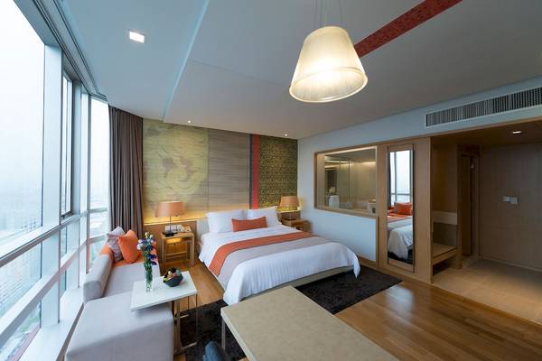 Schlafzimmer des Pathumwan Princess Hotels mit großem Bett, Blick auf die Stadt und modernen Möbeln.