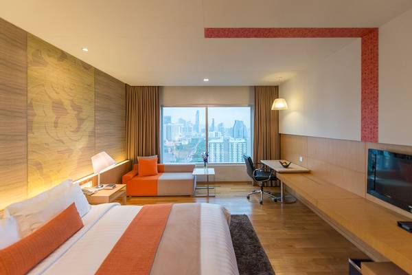 Schlafzimmer im Pathumwan Princess Hotel mit Stadtblick, bequemem Bett und Arbeitsbereich.
