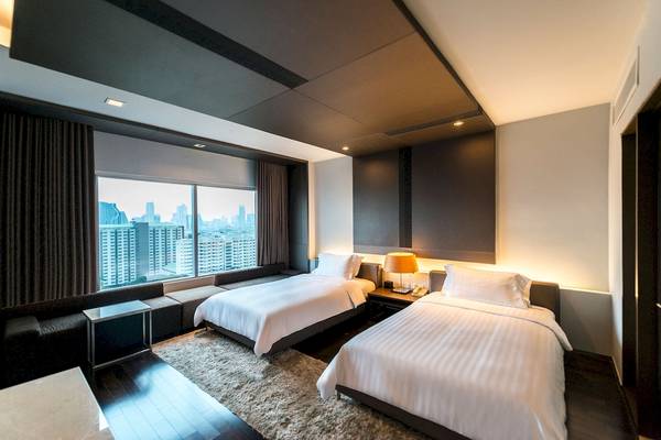 Schlafzimmer im Pathumwan Princess Hotel mit zwei Betten und Stadtblick.