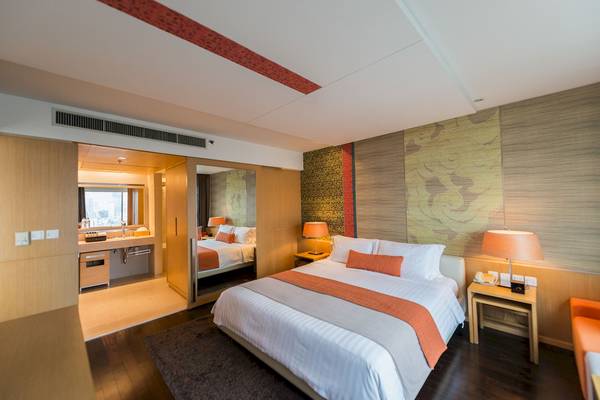 Schlafzimmer im Pathumwan Princess Hotel mit Bett, Nachttischen und Lampen.