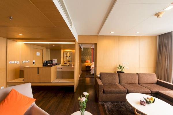 Wohnzimmer im Pathumwan Princess Hotel mit Sofa, Tisch und Blumen.