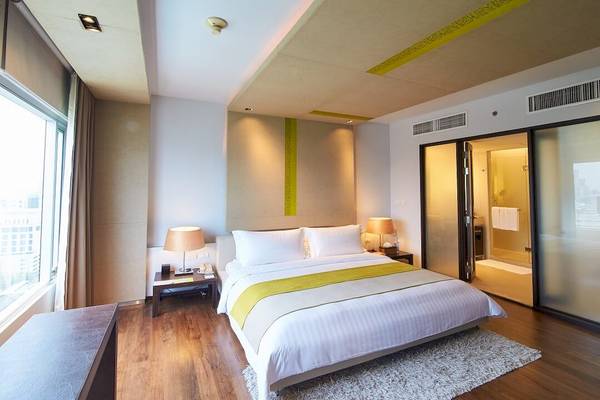 Schlafzimmer im Pathumwan Princess Hotel mit großem Bett und Stadtblick.