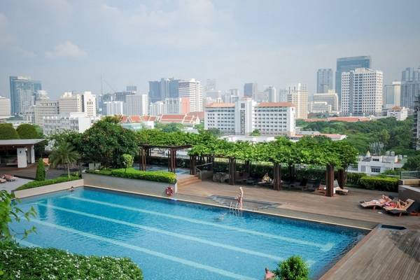 Aussicht auf den Pool im Pathumwan Princess Hotel mit Menschen, die schwimmen und sich entspannen.