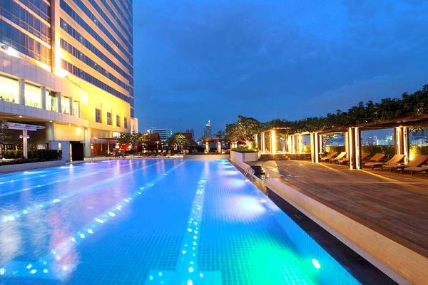 Außenpool des Pathumwan Princess Hotels bei Nacht mit blauen Lichtern.