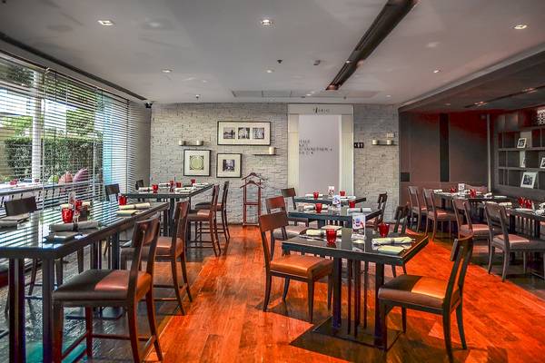 Innenansicht des Restaurants im Pathumwan Princess Hotel mit eingerichteten Tischen und Stühlen.