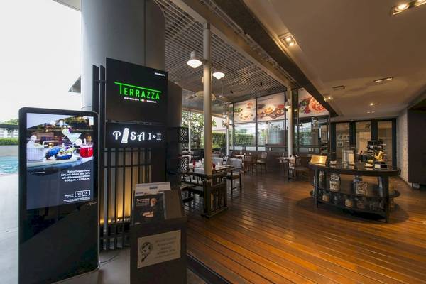 Innenansicht des Restaurants im Pathumwan Princess Hotel mit Tisch, Stühlen und Menütafeln.