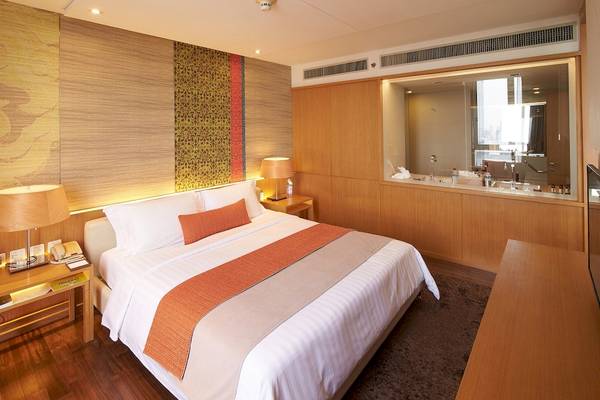 Hotelzimmer im Pathumwan Princess Hotel mit einem großen Bett und Dekor.