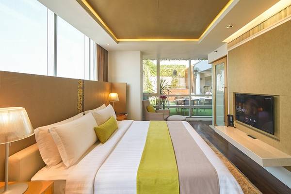 Schlafzimmer im Pathumwan Princess Hotel mit großem Bett, Lampen und Fernseher.