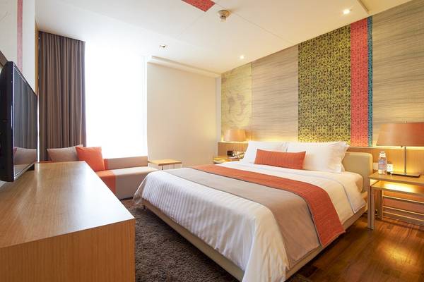Pathumwan Princess Hotelzimmer mit Doppelbett, Fernseher und Sitzbereich.