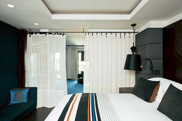 Sofitel Agadir Thalassa Sea & Spa Hotel Schlafzimmer mit Doppelbett, blauem Teppich und weißen Vorhängen.