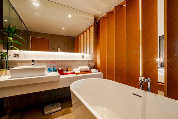 Badezimmer im Ramada Resort by Wyndham Khao Lak mit Badewanne, Waschbecken und Spiegel.