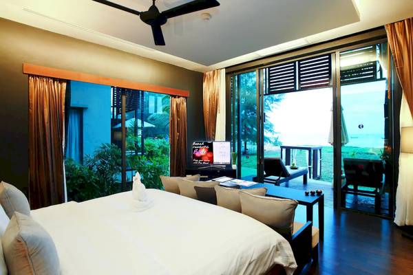 Innenansicht eines Hotelzimmers im Ramada Resort Khao Lak mit großem Bett, Fernseher und Balkon.