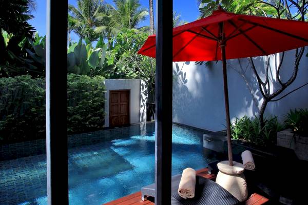 Blick aus dem Zimmer im Ramada Resort by Wyndham Khao Lak auf einen Pool mit einem roten Sonnenschirm.