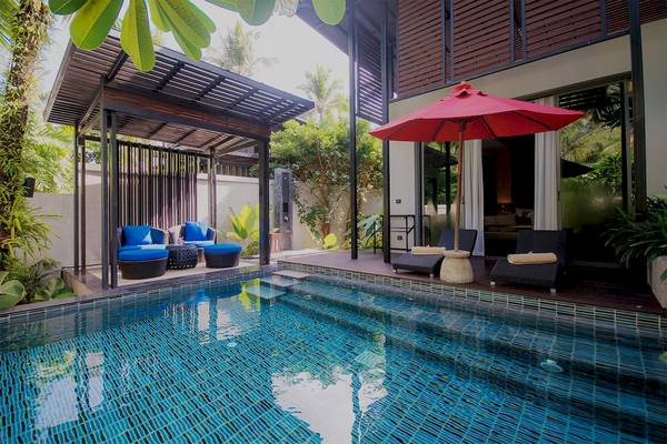 Swimmingpool im Ramada Resort by Wyndham Khao Lak mit Sonnenschirm und Loungemöbeln.