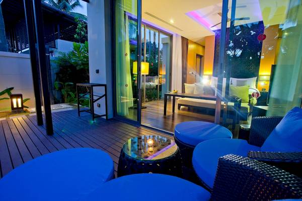 Außenbereich des Ramada Resort by Wyndham Khao Lak mit blauen Möbeln und Glastüren.