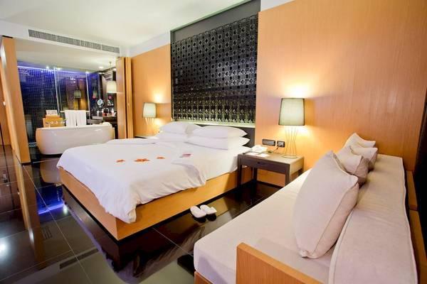 Hotelzimmer im Ramada Resort by Wyndham Khao Lak mit Bett, Sofa, Badewanne und Lampen.