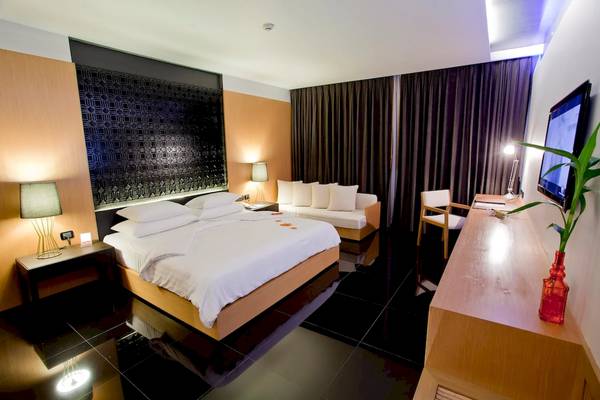 Hotelzimmer im Ramada Resort by Wyndham Khao Lak mit Doppelbett, Sofa, Schreibtisch und Fernseher.