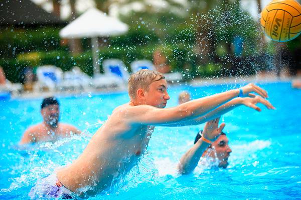 Junge wirft Wasserball im Schwimmbad von Selectum Family Comfort Side