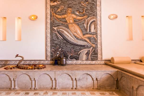 Innenbereich des Djerba Plaza Thalasso & Spa mit Wandmosaik und Sitzbank.