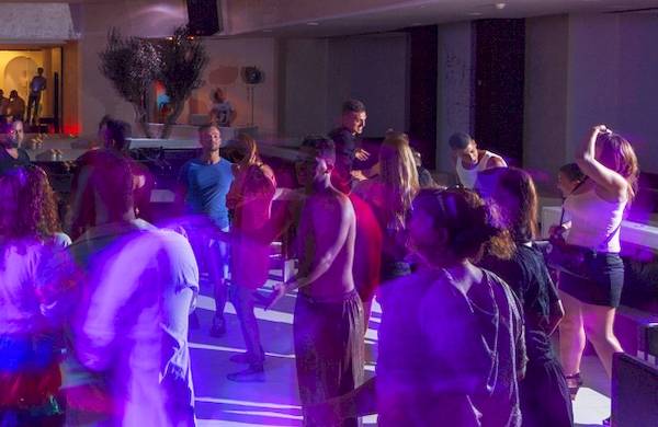 Gäste tanzen in der Hotellounge bei einer Party mit bunten Lichtern.