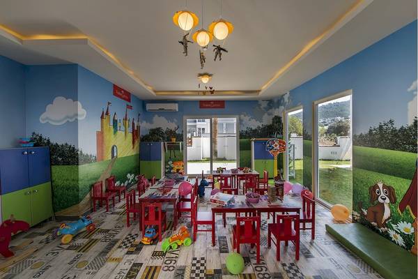Voyage Torba Kinderzimmer mit bunten Wänden, Spielzeug und roten Stühlen.