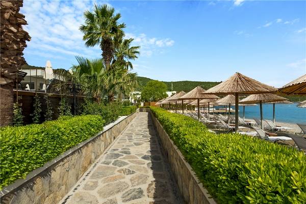 Strandweg mit grünen Büschen und Sonnenschirmen zum Voyage Torba Hotel