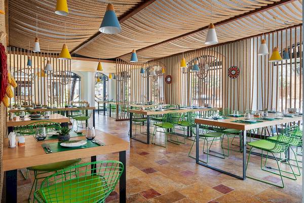 Innenansicht des Restaurants im Voyage Torba Hotel mit grünen Stühlen und Holztischen.