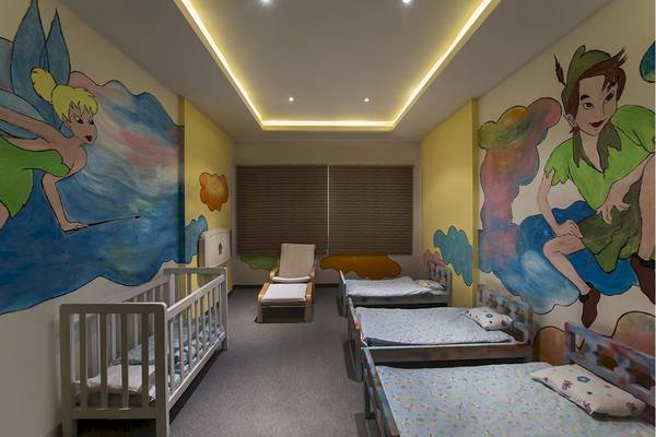 Kinderzimmer im Voyage Torba Hotel mit farbenfrohen Wandgemälden von Tinkerbell und Peter Pan, mehreren Betten und einem Stuhl.