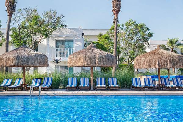 Pool-Lounge-Bereich des Voyage Torba Hotels mit Sonnenliegen und Strohschirmen.