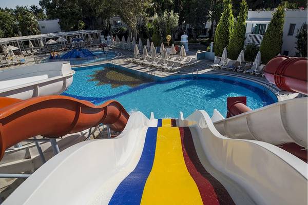 Wasserrutschen und Pool im Voyage Torba Hotel mit Liegestühlen und Sonnenschirmen.