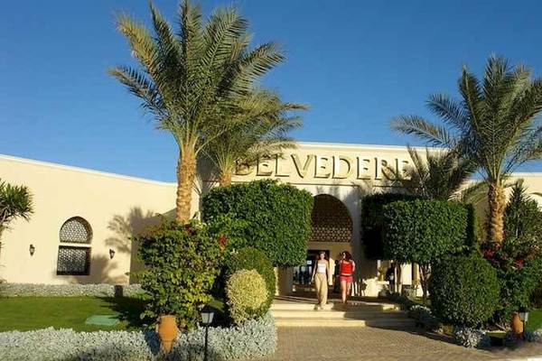 Zwei Personen vor dem Jaz Belvedere Resort mit Palmen und Gebäuden im Hintergrund.