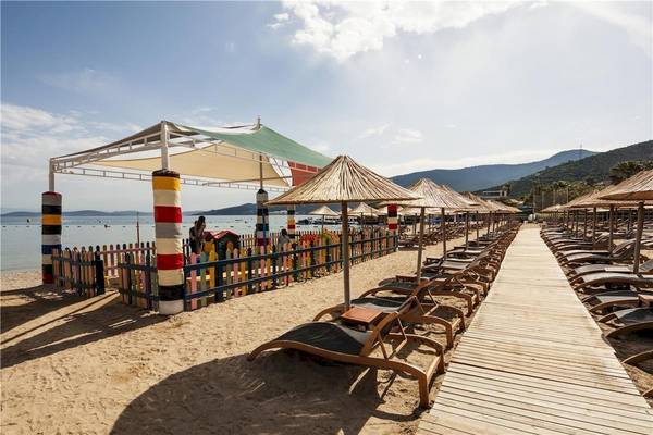 Außenbereich des Voyage Torba Hotels mit Sonnenliegen und Sonnenschirmen am Strand