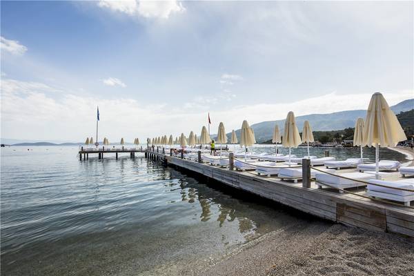 Foto der Terrasse des Voyage Torba Hotels mit Sonnenliegen und Schirmen am Wasser