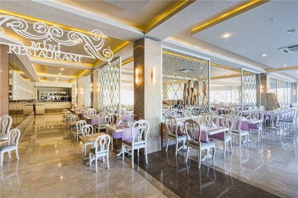 Innenansicht des Mini Restaurants im Voyage Torba Hotel mit gedeckten Tischen und Stühlen.