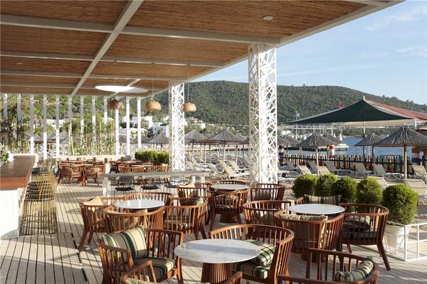 Terrasse des Voyage Torba Hotels mit Sitzgelegenheiten am Strand und Blick auf das Meer.