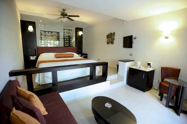 Hotelzimmer im Punta Cana Princess mit Bett, Sofa, Tisch, Fernseher und Klimaanlage.