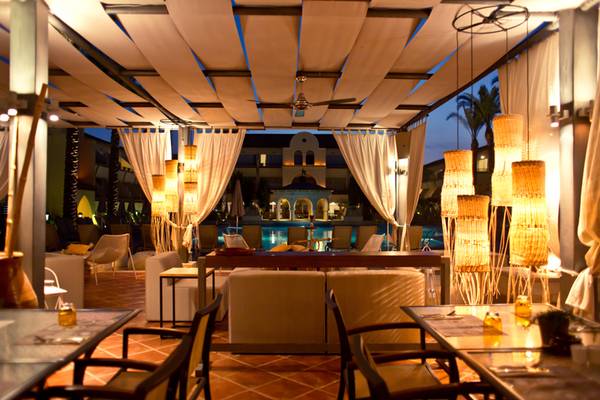 Abendaufnahme des Restaurants im Napa Plaza Hotel mit Außenbereich, Tischen und Stühlen unter einem Dach mit Vorhängen und Lampen.